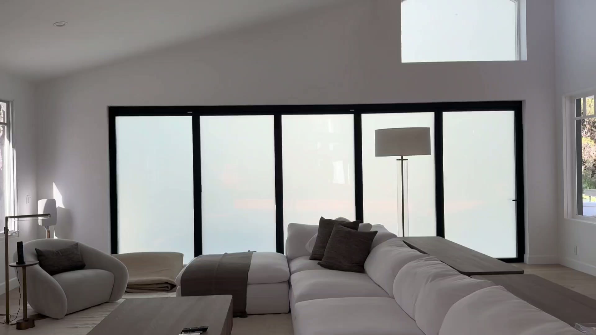 A finished living room with wide black-framed windows and frosted privacy glass
