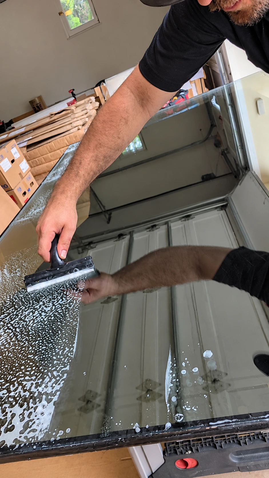 An installer cleaning a glass panel with a squeegee before film application